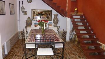 A dining area with a patterned table, chairs, and a staircase.
