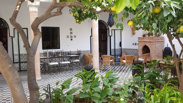 Un patio con suelo a cuadros, mobiliario exterior y una fuente.