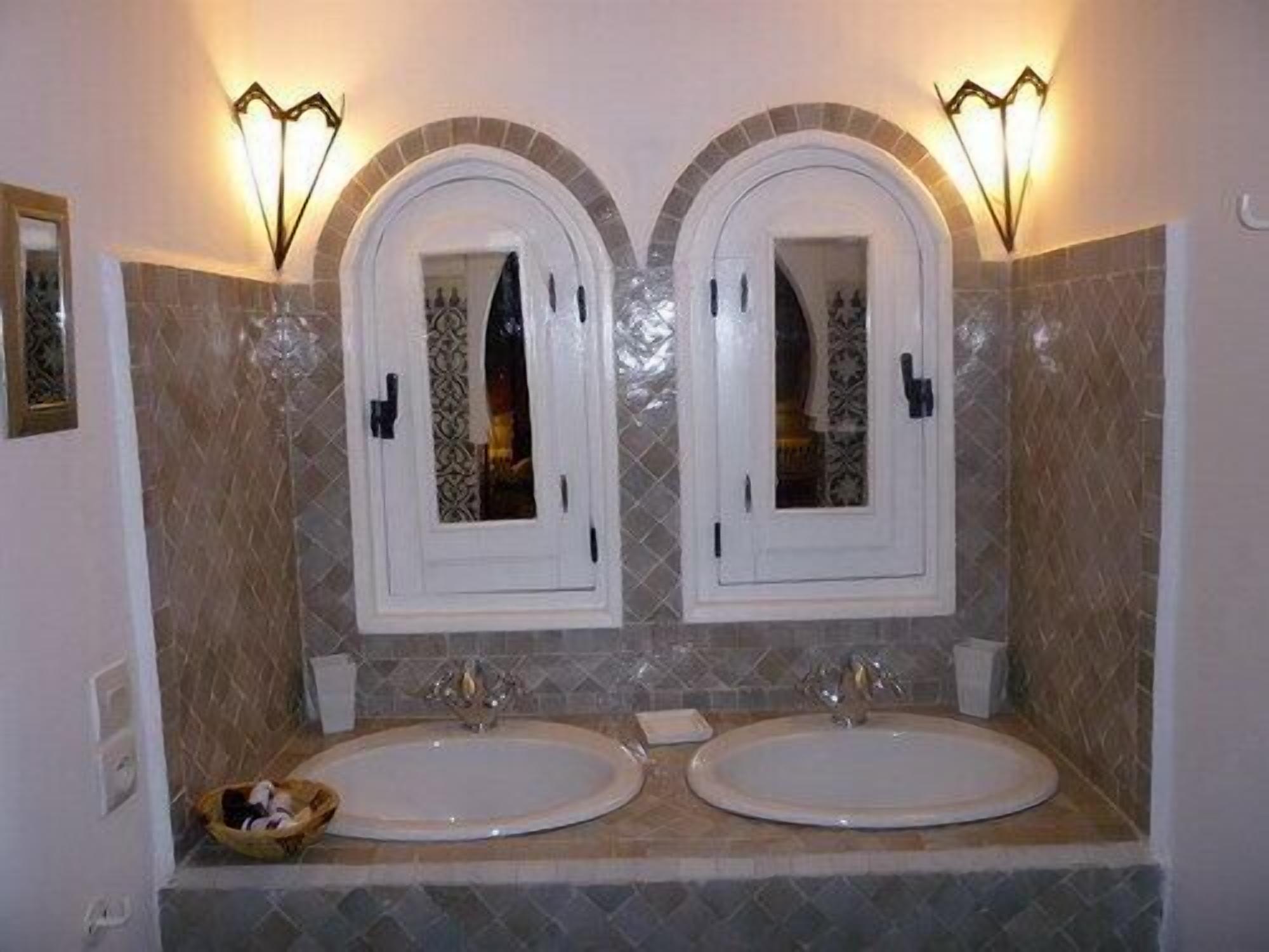 A bathroom with two sinks, a mirror, and wall sconces.