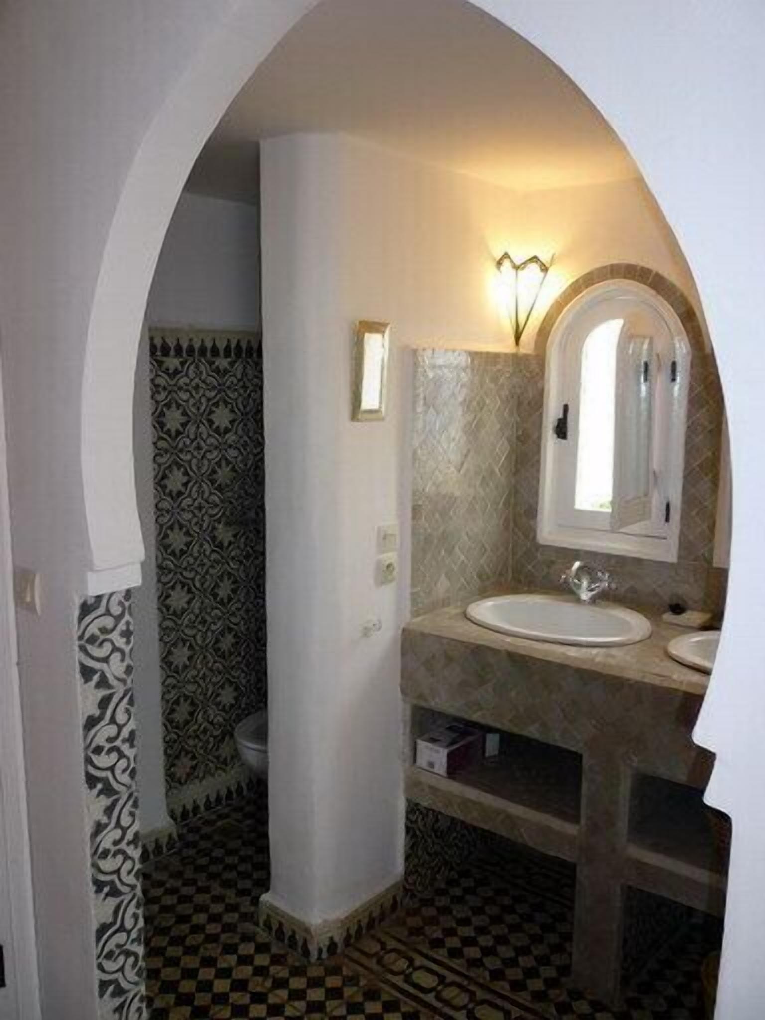 A bathroom with a checkered floor, a sink with a mirror, and patterned walls.