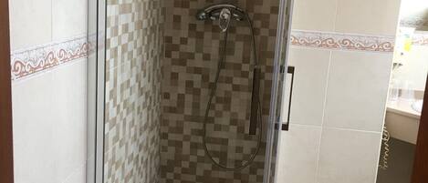 A glass-enclosed shower with a checkered tile pattern on the walls and a showerhead.
