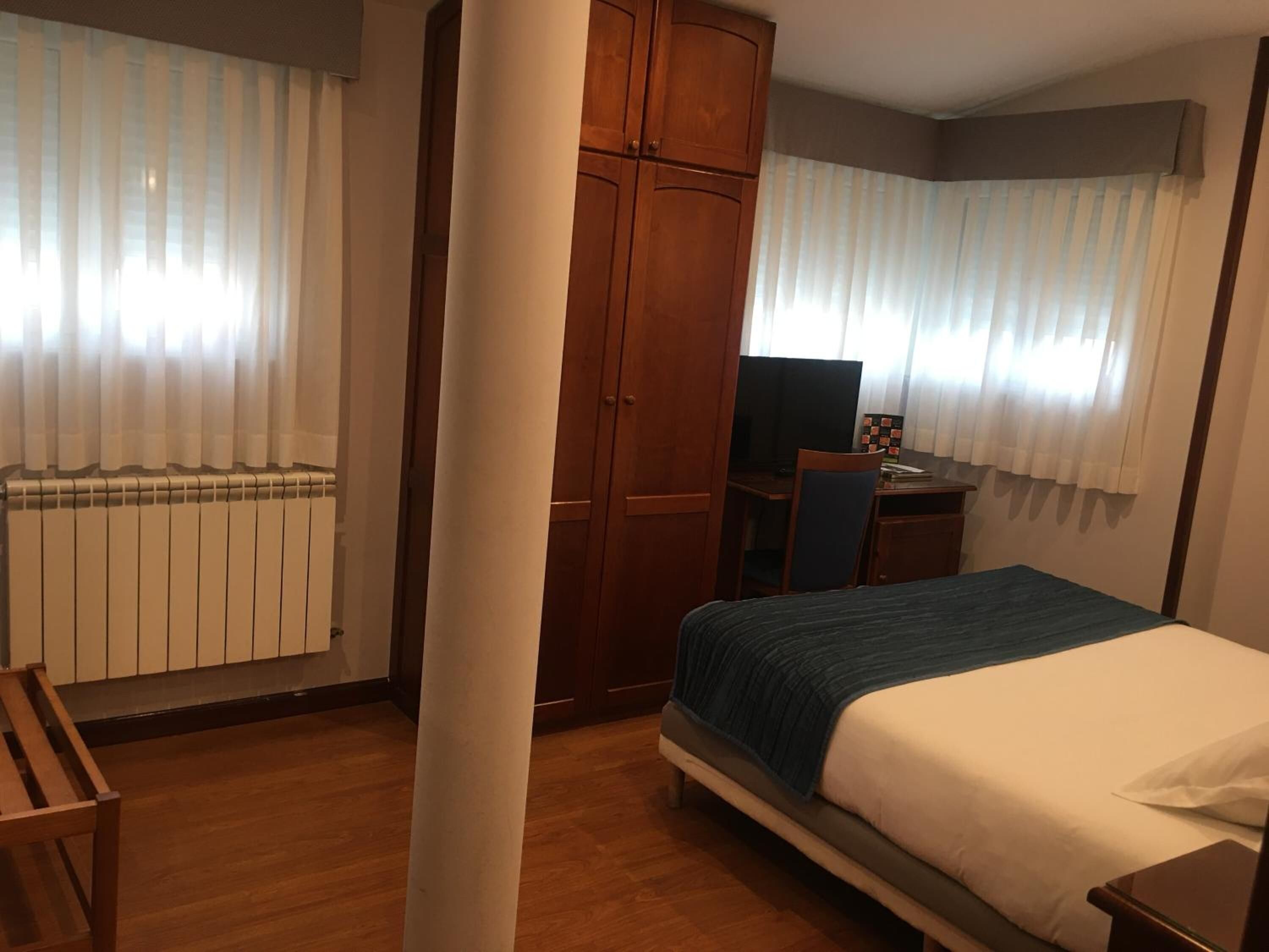 A bedroom with a bed, a desk, a chair, and a wardrobe.