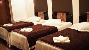 Une chambre d’hôtel avec trois lits simples, chacun recouvert d’une couverture marron et agrémenté d’oreillers blancs.