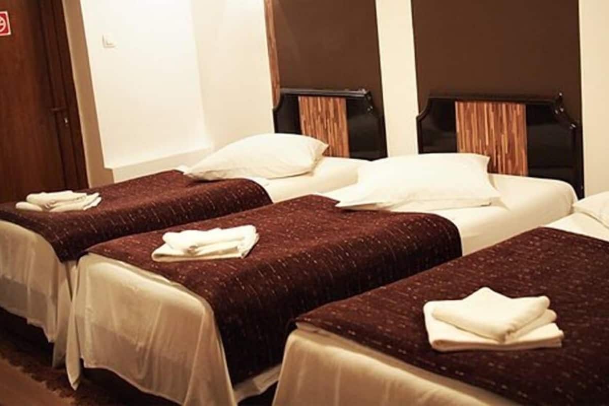 Ett hotellrum med tre separata sängar, var och en med ett brunt överkast och vita kuddar.