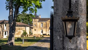 Un bâtiment en pierre, de style architectural traditionnel, avec une pelouse bien entretenue et un lampadaire décoratif.