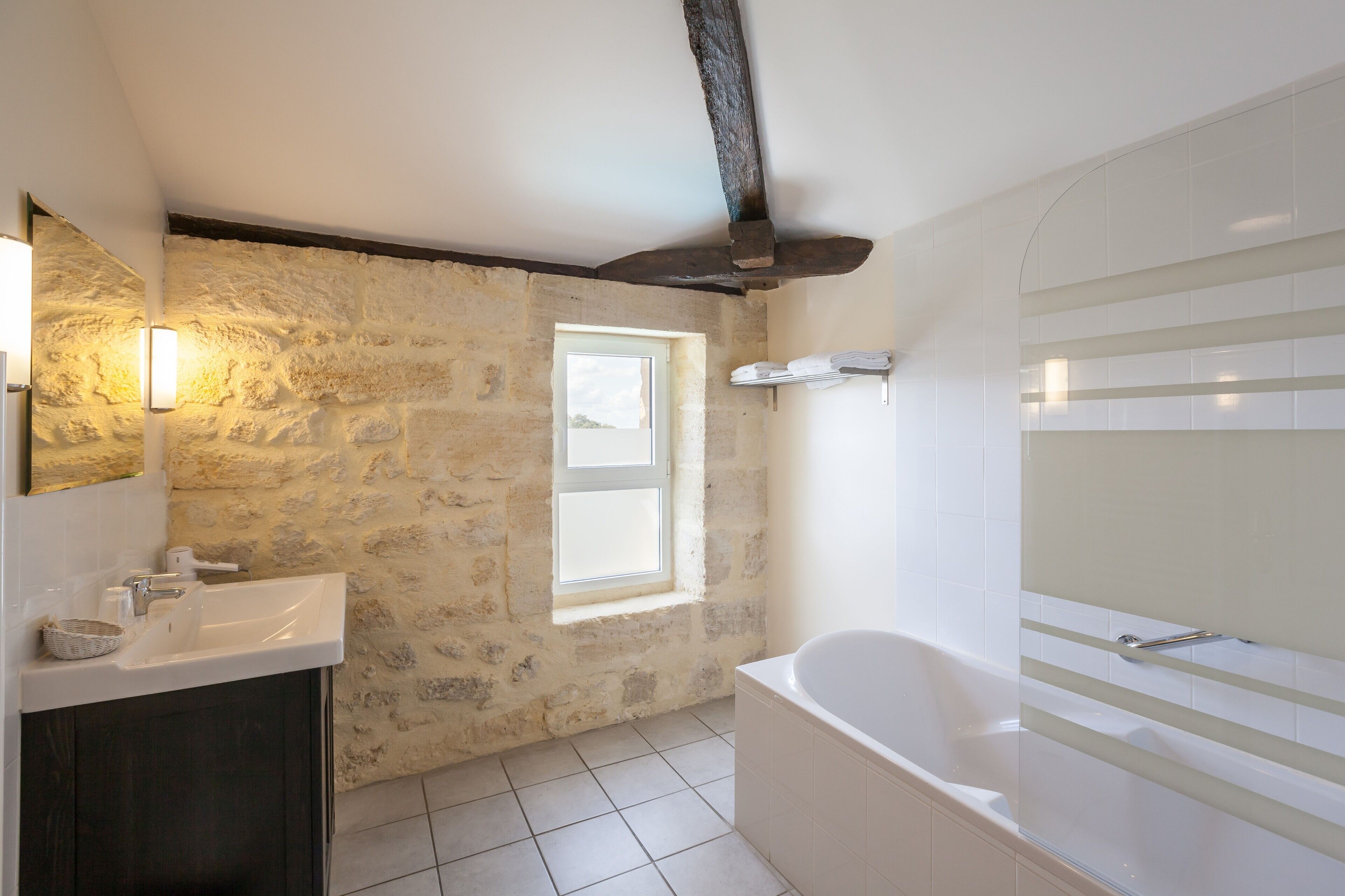 Ein Badezimmer mit Steinwand, Fenster, Waschbecken und Badewanne.