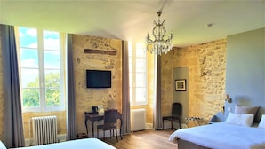 Une chambre d’hôtel avec deux lits, un bureau avec une chaise, une télévision et un lustre.
