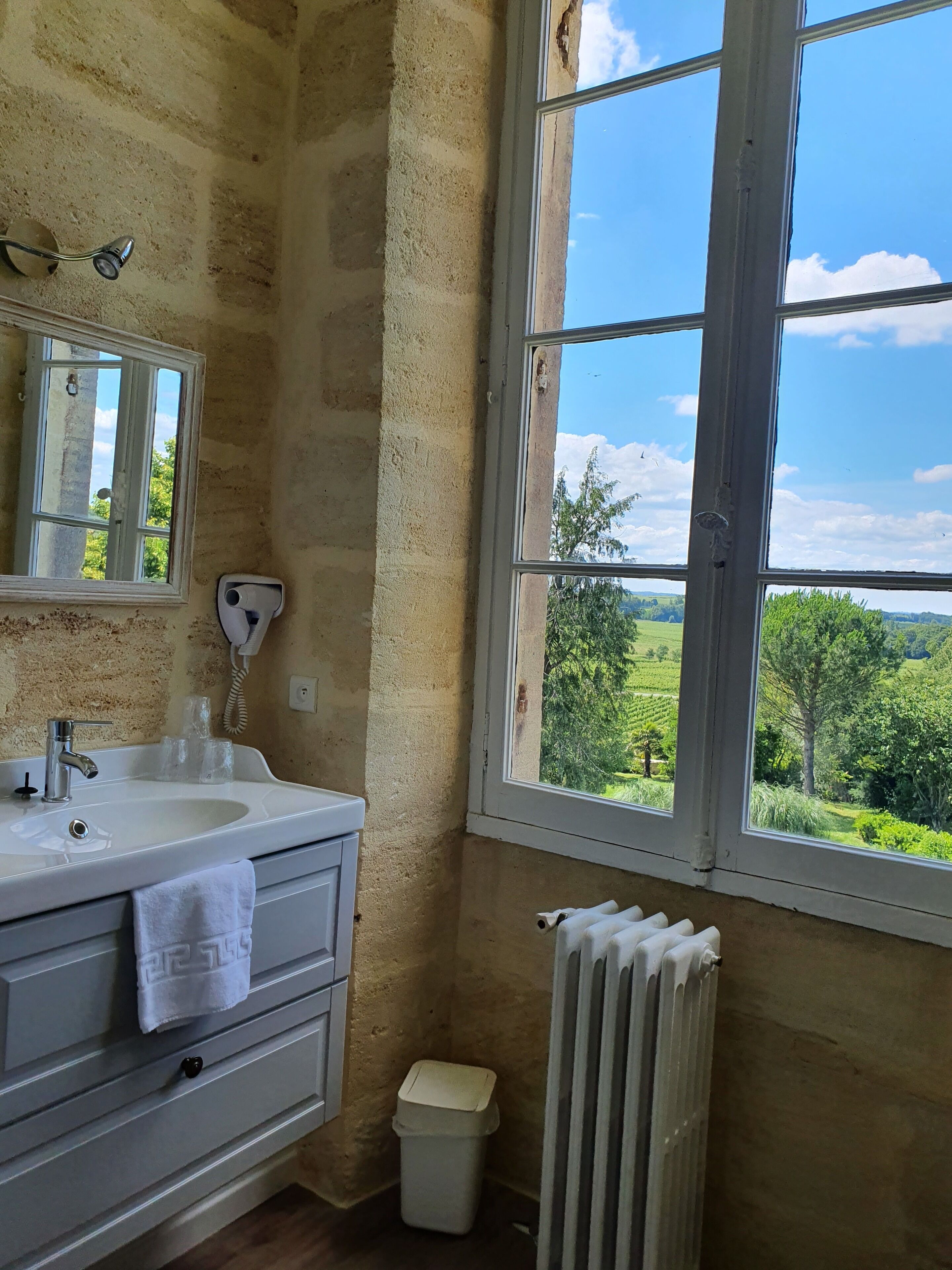 Un baño con lavamanos, espejo y ventana.