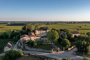 Una extensa propiedad con varios edificios, rodeada de viñedos y campos abiertos.