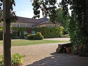 A courtyard with a stone pathway leading to a building with a tiled roof.