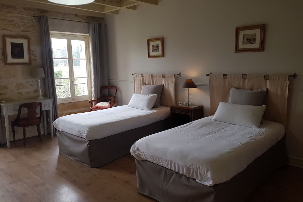 A room with two beds, a desk, and a chair.