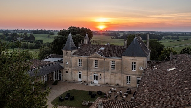 Un grand bâtiment historique doté de nombreuses tours et d’une cour intérieure aménagée avec des espaces de repos en plein air.