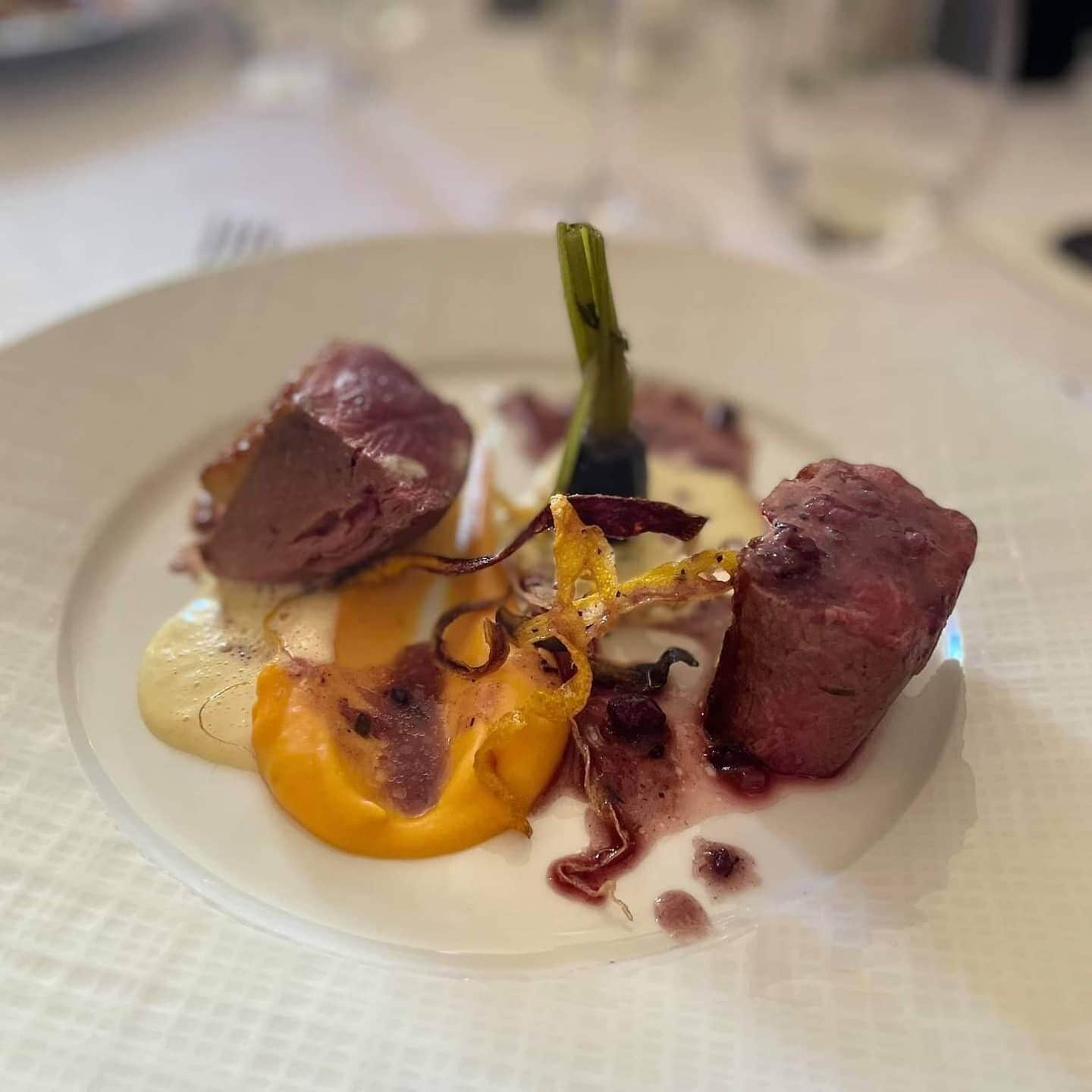 A plate with a dish consisting of meat, vegetables, and sauce.
