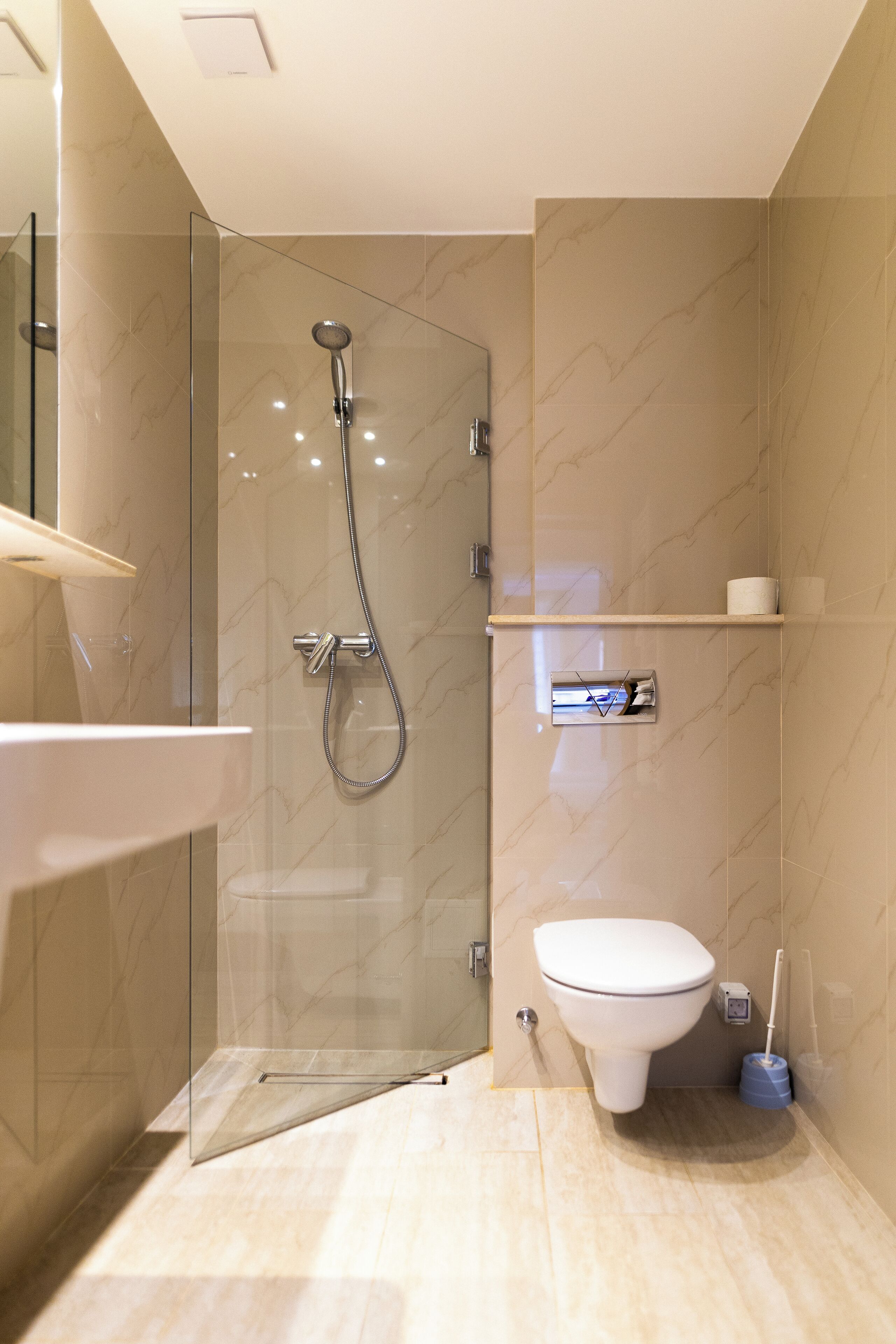 Un bagno moderno con doccia vetrata, un water bianco e un pavimento in marmo.