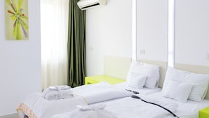 Une chambre d’hôtel moderne avec un grand lit, une table de chevet, un appareil de climatisation et un mur d’accent d’un vert vif.