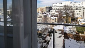 Une vue depuis une fenêtre donnant sur un paysage urbain enneigé, avec de nombreux bâtiments et un ciel dégagé.