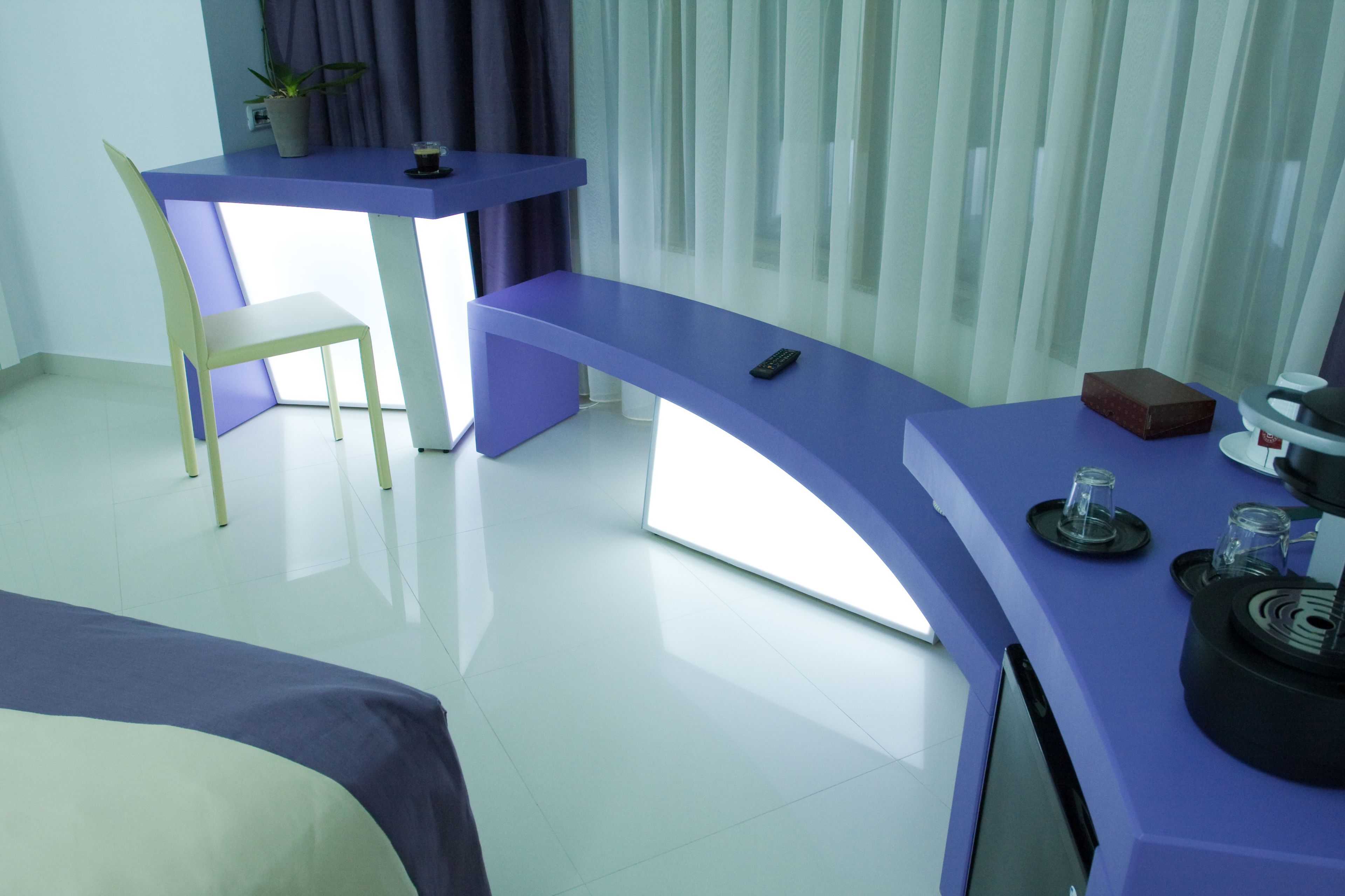 A modern room with a purple desk, a chair, and a TV.