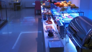 Un espace buffet proposant une variété de plats, un écran de projection affichant un motif floral et un coin barbecue.