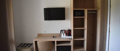 A compact room with a desk, chair, and a TV mounted on the wall.