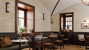 A cozy seating area with a sofa, round tables, and wooden chairs. - Andrássy Kúria & Spa (Tarcal)