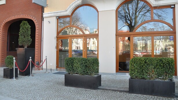 A hotel entrance with a brick facade, large arched windows, and a signboard. - Atrium Hotel (Elblag)