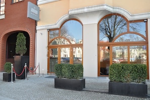 A hotel entrance with a brick facade, large arched windows, and a signboard. - Atrium Hotel (Elblag)