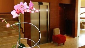 A modern interior with a wooden floor, a red ottoman, and a large metallic refrigerator. - Atrium Hotel (Elblag)
