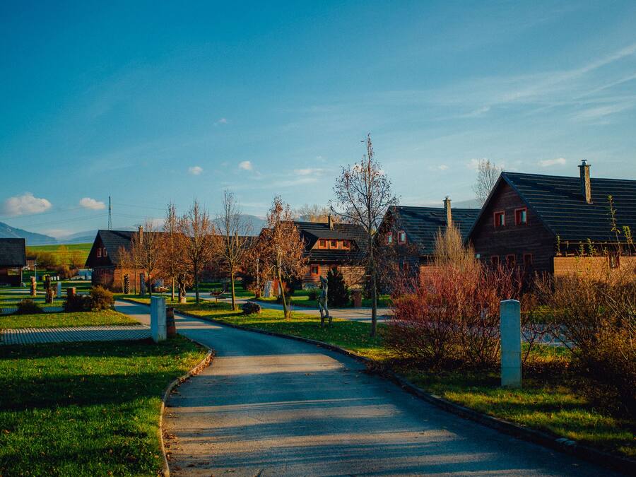 A residential street with houses, a clear sky, and a winding road.