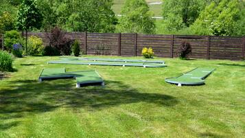 Un espacio cubierto de césped con cuatro áreas de práctica de putting dispuestas en forma de rombo.