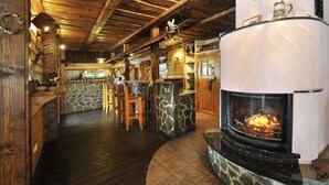 Een gezellig interieur met een stenen openhaard, een houten bar en rustieke decoratie.