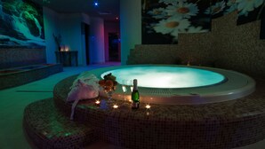 Een bubbelbad met een mozaïek omlijsting, een fles champagne en een schaal fruit.