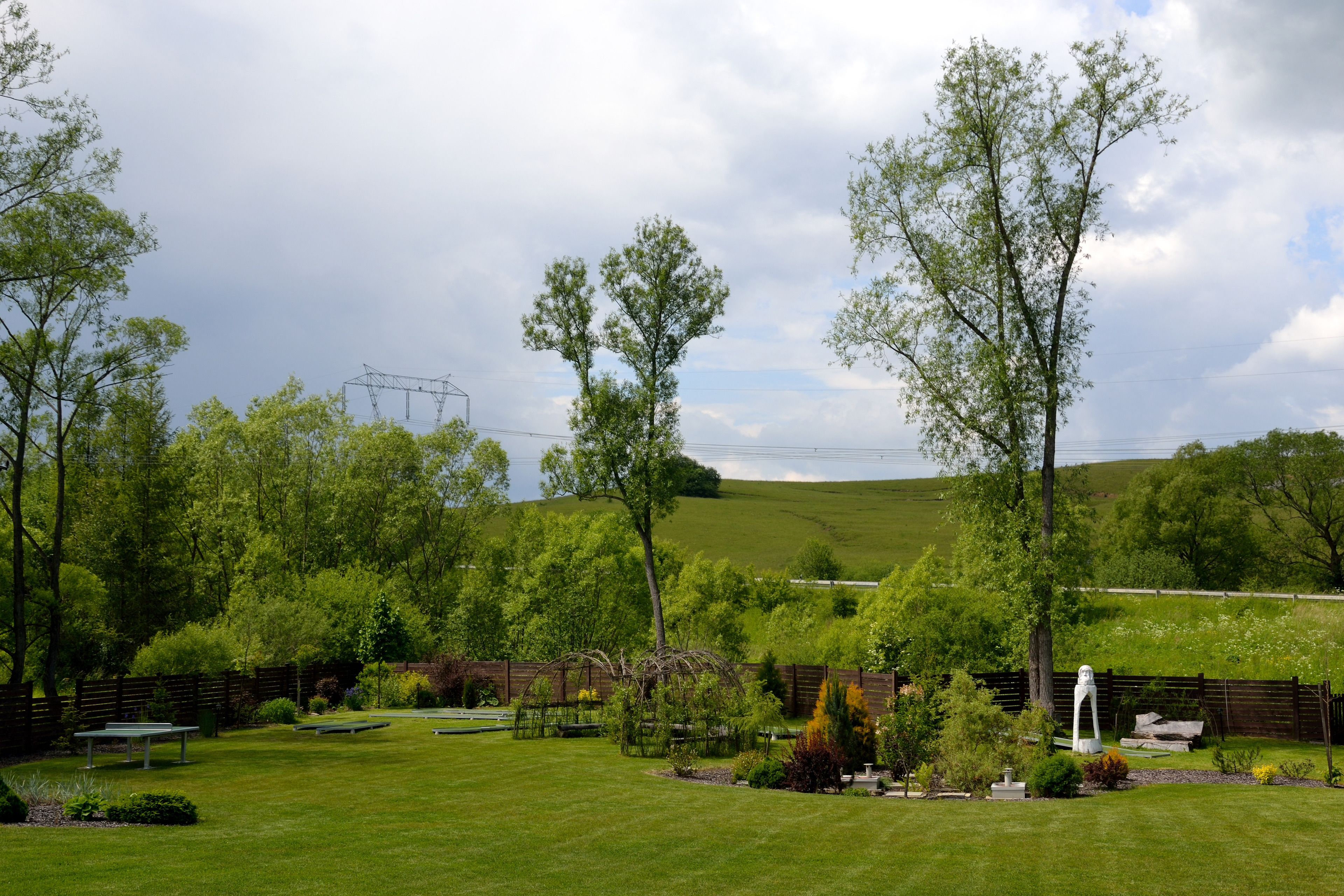 Un giardino curato con diverse specie di alberi, un gazebo e un tavolo da picnic.
