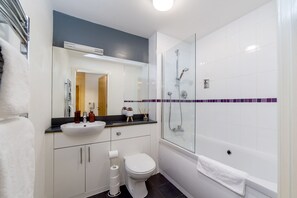 Une salle de bain moderne avec un lavabo, des toilettes et une baignoire, le tout de couleur blanche.