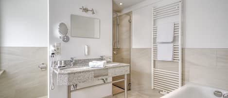 A modern bathroom with a freestanding bathtub, a walk-in shower, and a vanity with a mirror and towel rack.