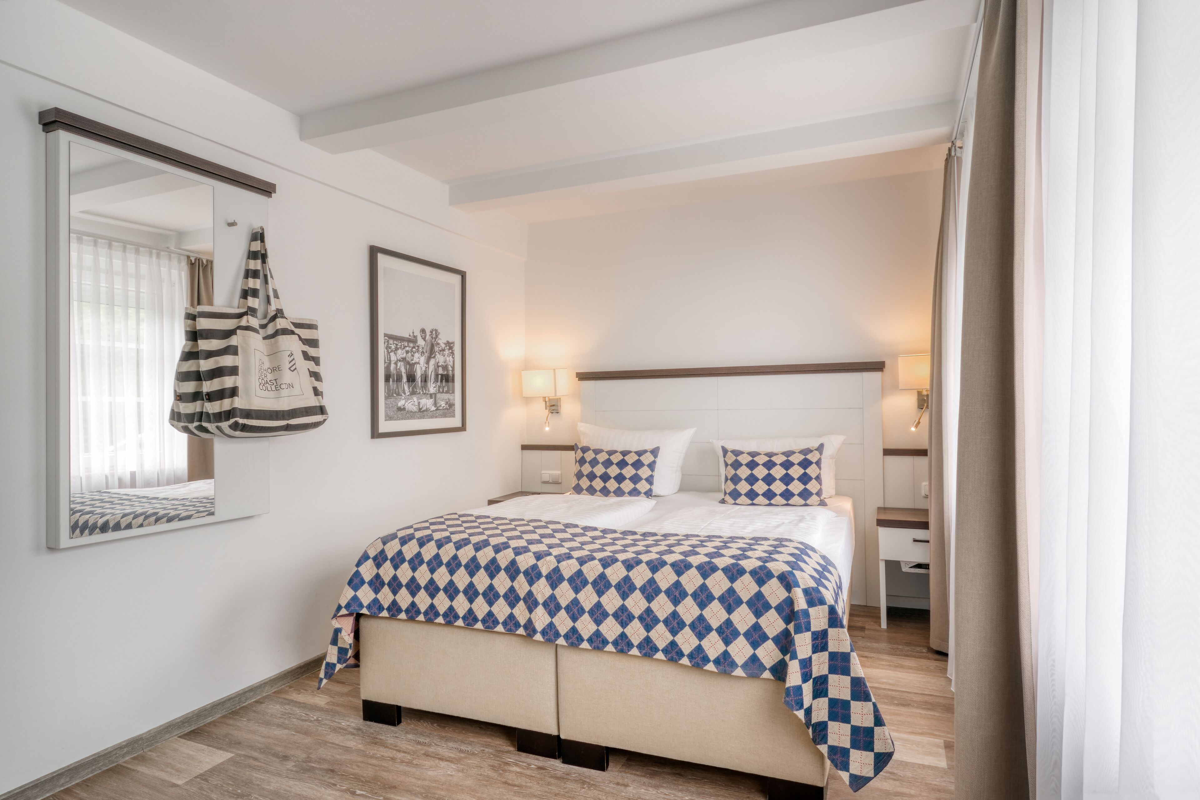 Une chambre à coucher avec un lit, des tables de chevet, un miroir et un sac suspendu.