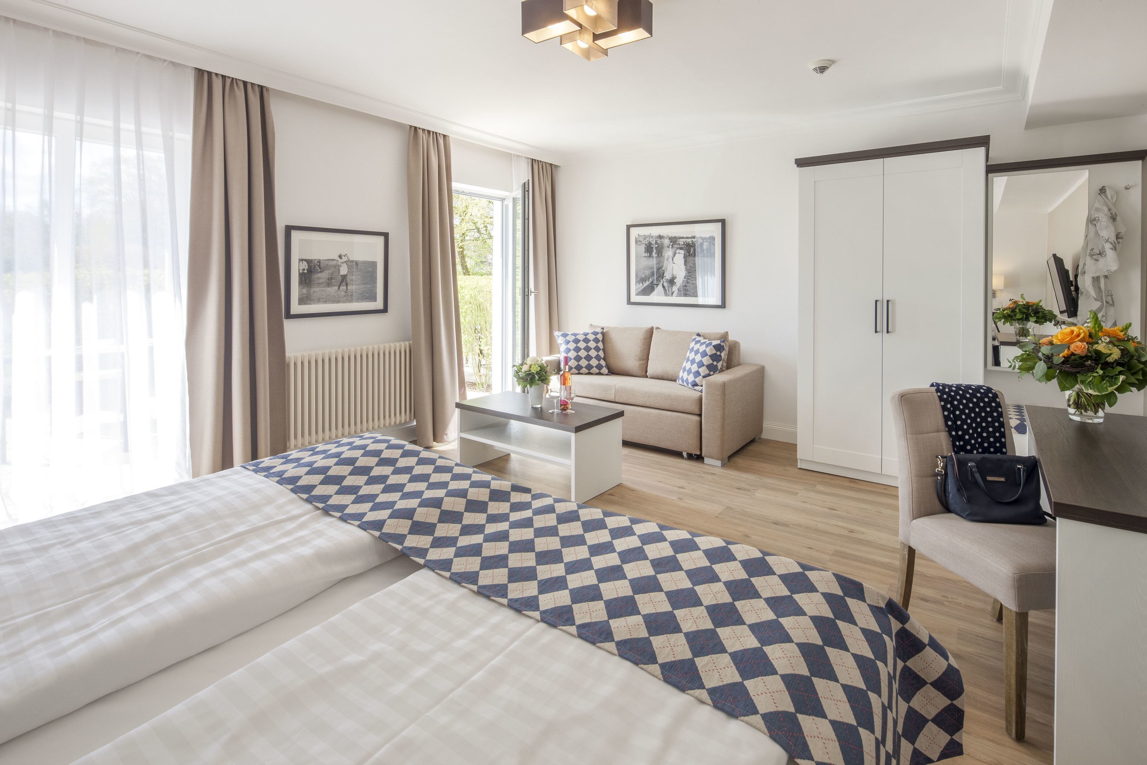 Una habitación de hotel con una cama, un sofá, una mesa de centro, una silla, un armario y un espejo.