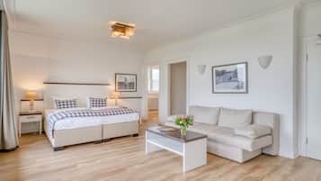 Een moderne hotelkamer met een tweepersoonsbed, een slaapbank, een bijzettafeltje en een klein bureau met lamp.