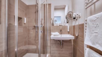 A modern bathroom with a glass-enclosed shower, a sink, and a towel rack.