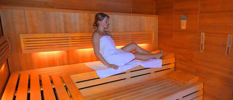 Una sauna con bancos de madera y un banco con una toalla.