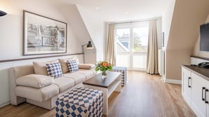 A modern living room with a sofa, coffee table, and a painting on the wall. - Strandgrün Golf- & Spa Resort (Timmendorfer Strand)