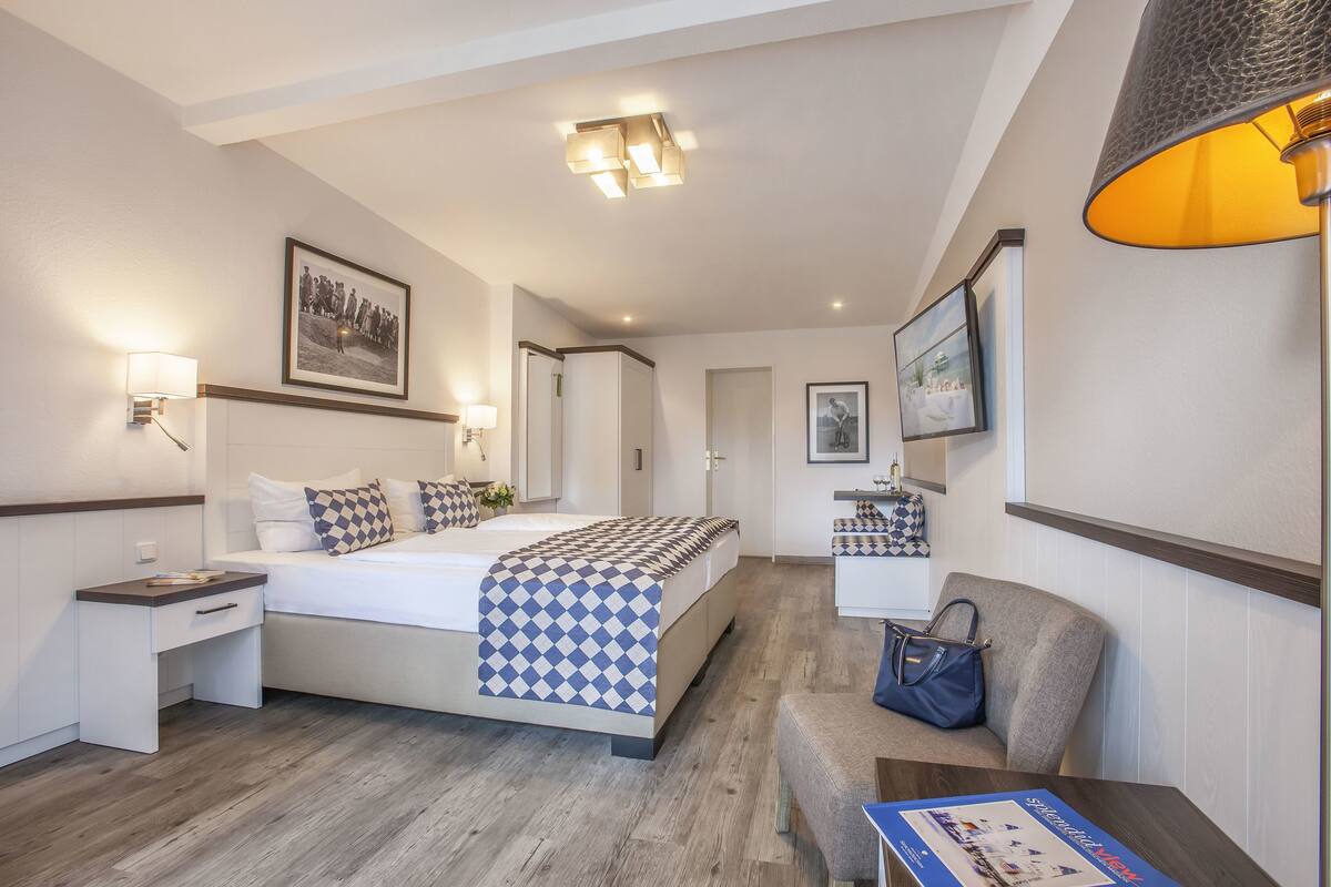 A hotel room with a bed, bedside tables, a desk, a chair, and a lamp.
