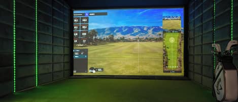 A room with a large screen displaying a golf game interface, a golf bag, and green ambient lighting.