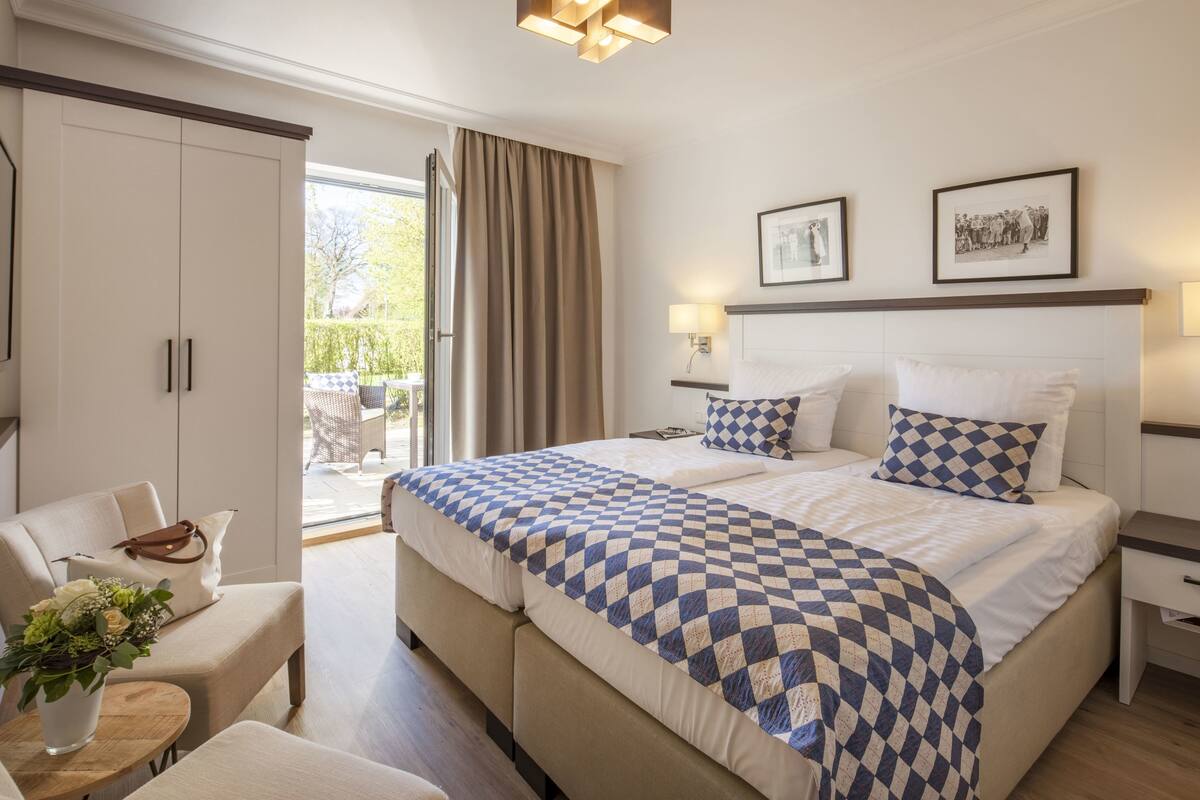 A hotel room with a large bed, a sofa, a desk, and a view of the outdoors.