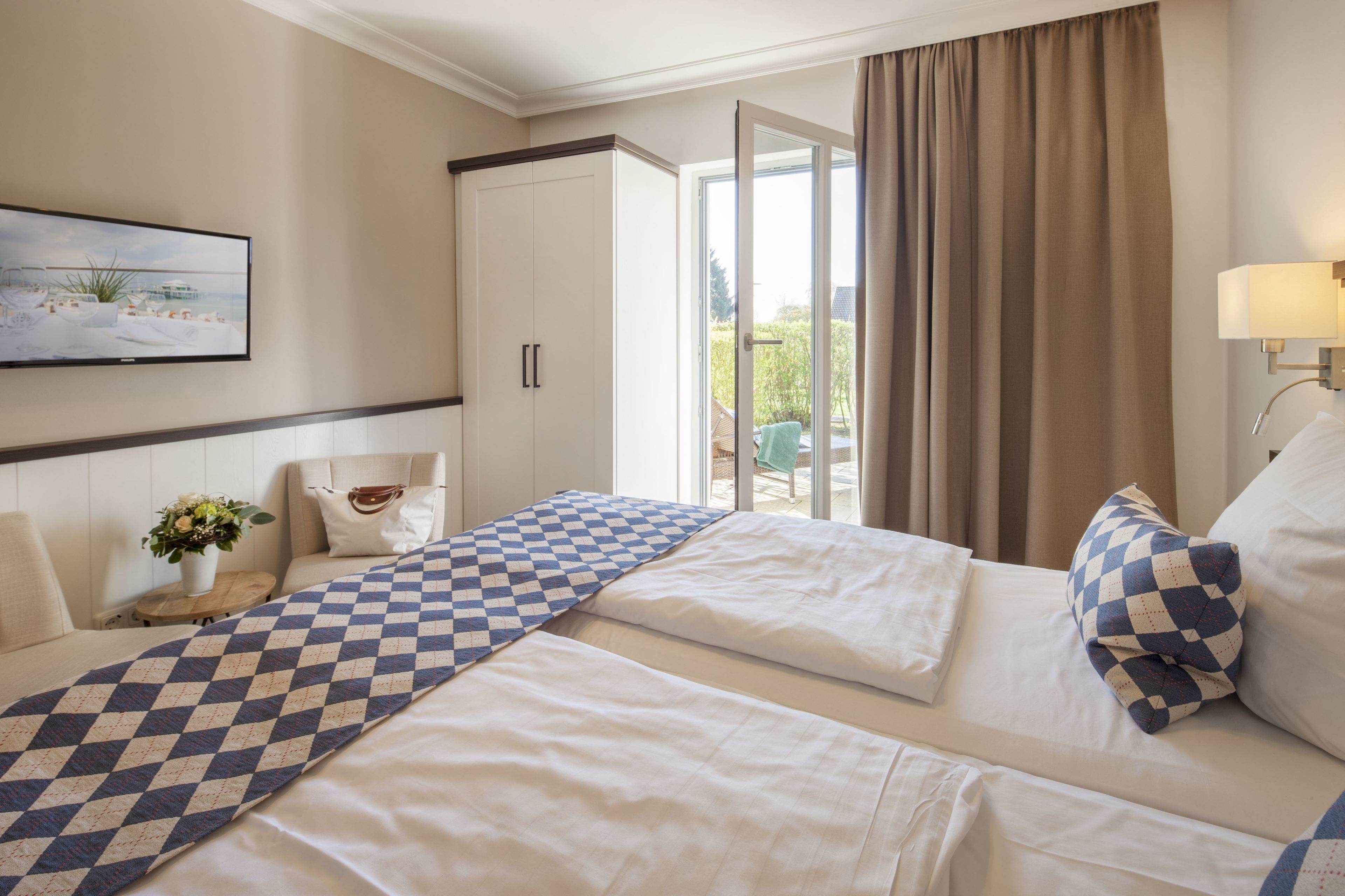 Habitación de hotel con dos camas, un ventanal amplio, un cuadro y vistas al exterior.