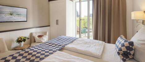 Habitación de hotel con dos camas, un ventanal amplio, un cuadro y vistas al exterior.