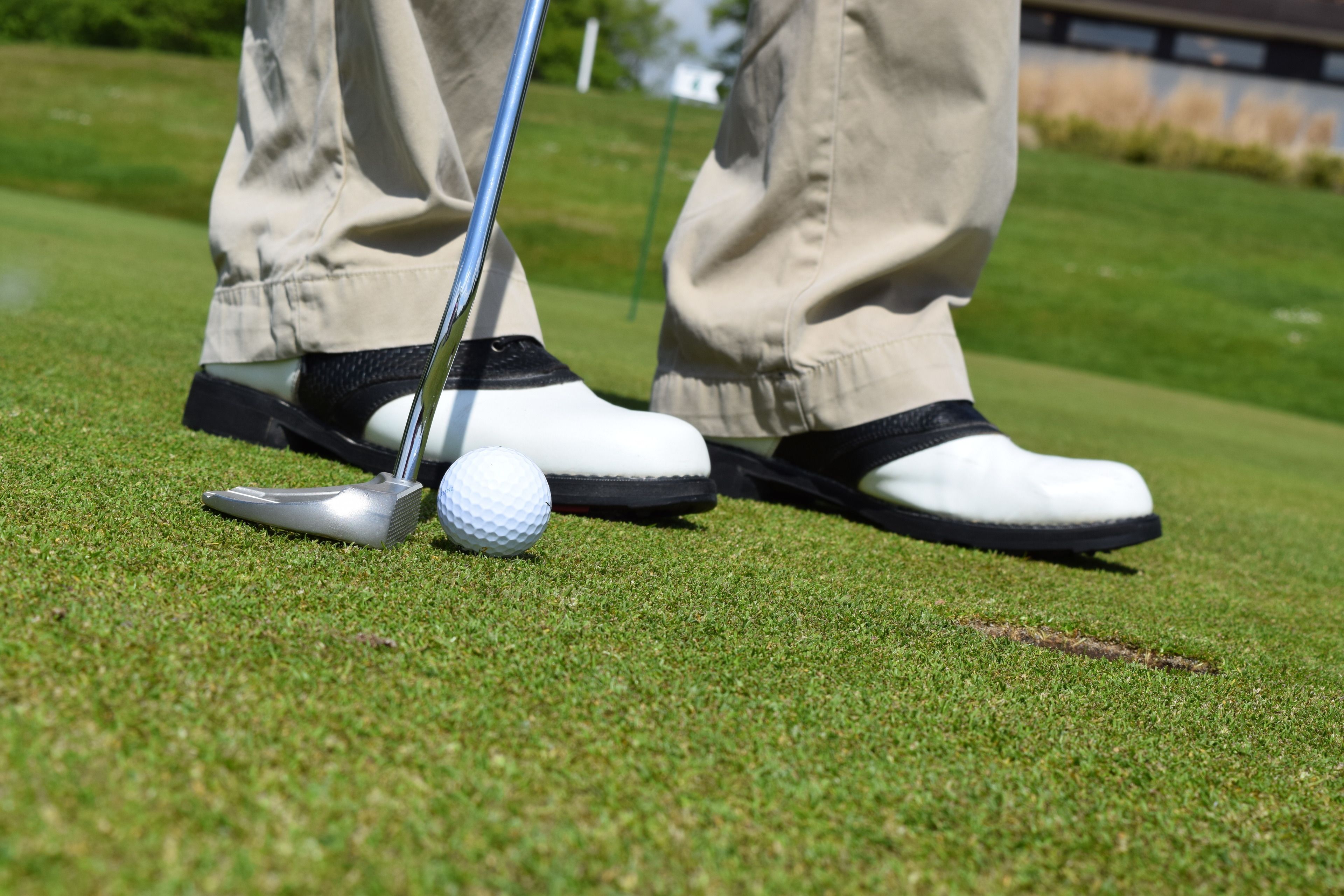 A golf ball on a tee with a golf club nearby.