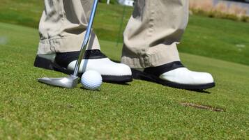 Een golfbal op een tee, met een golfclub in de buurt.