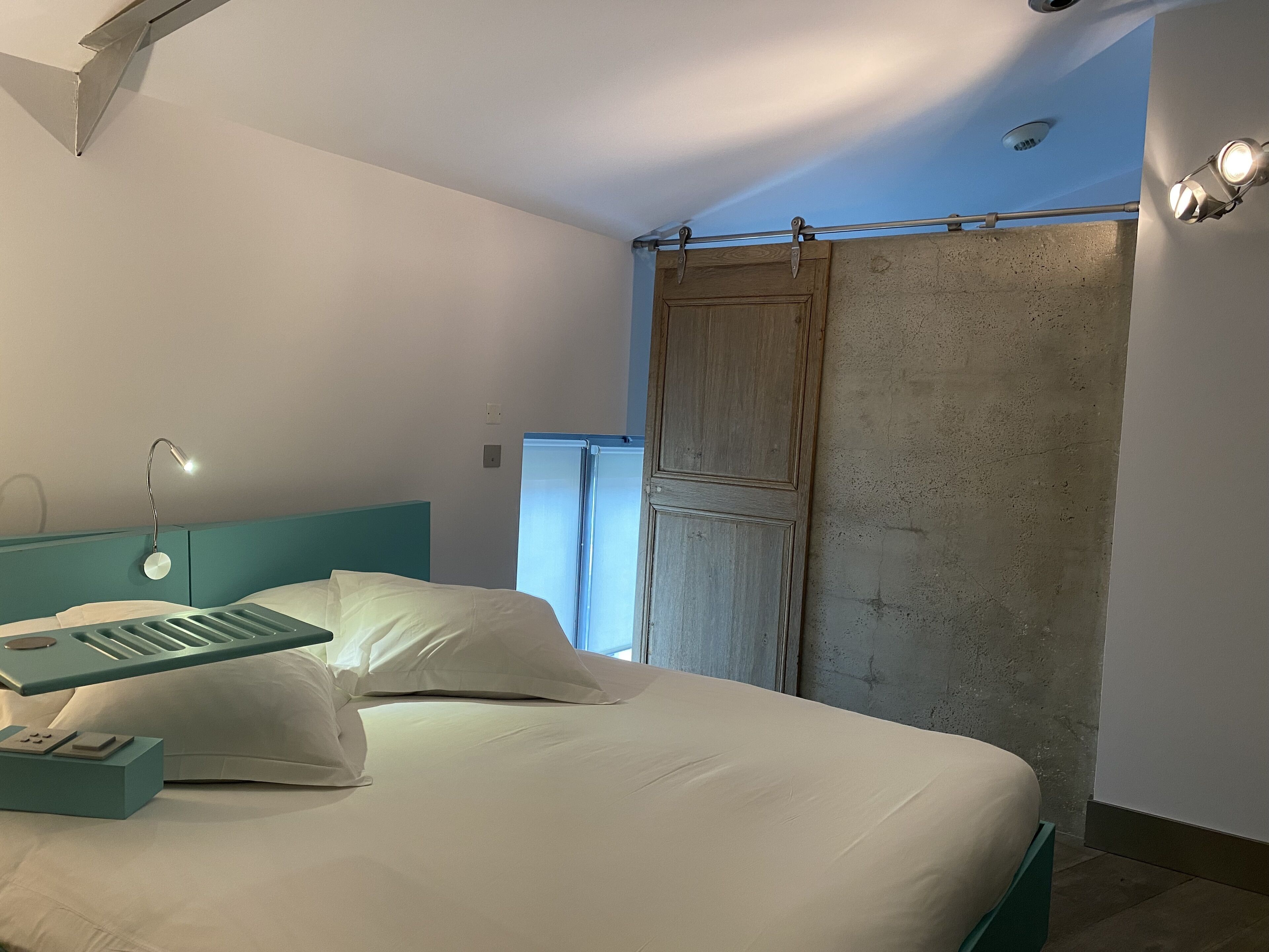 Un dormitorio moderno con cama, mesita de noche, escritorio y ventana con vistas.