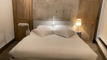 A single bed with white bedding, a bedside lamp, and wooden paneling on the walls.