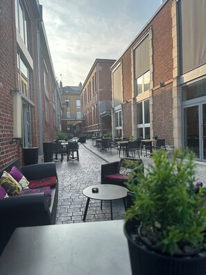 Un patio con mesas al aire libre, una planta en maceta y edificios de ladrillo.